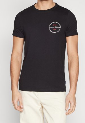 Czarna bawełniana koszulka z okrągłym dekoltem. Na froncie znajduje się okrągła grafika w kolorze czerwonym z białym napisem "NYC" oraz "Tommy Hilfiger 1985".