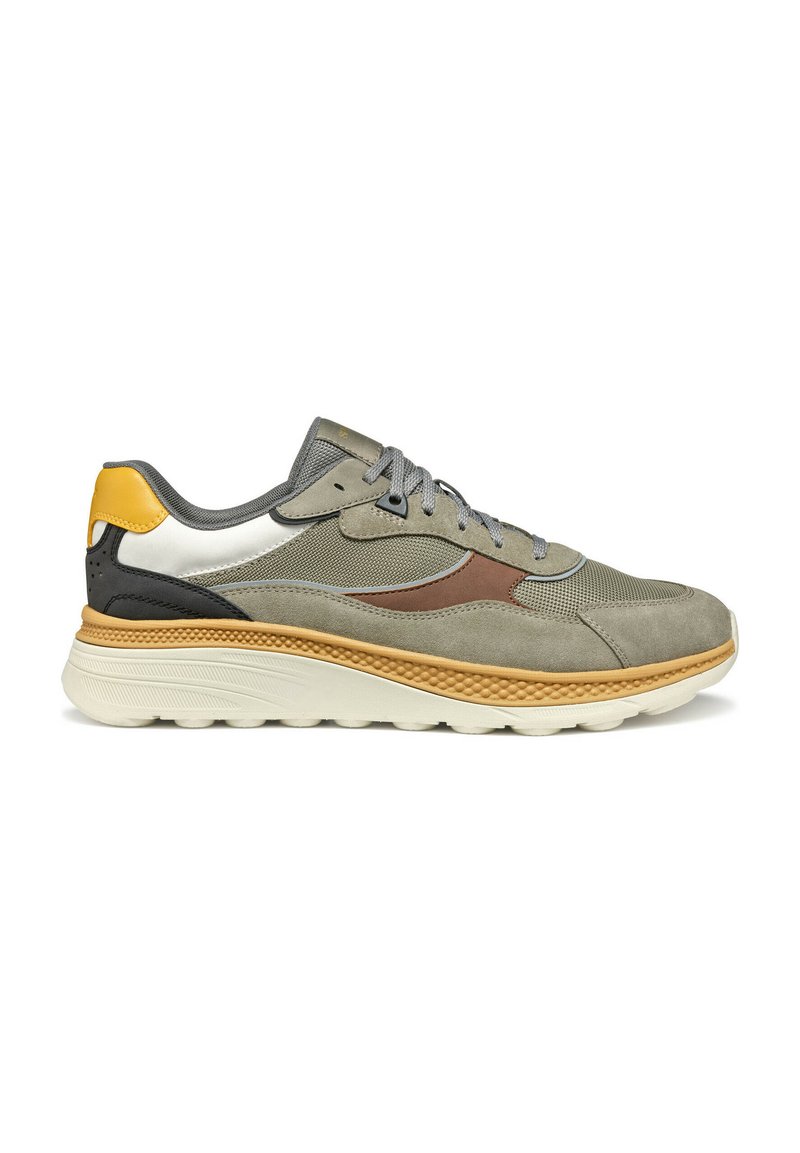 Sneaker grigio chiaro con materiali misti in suede e mesh. Presenta accenti gialli e neri, una suola beige texturizzata e lacci grigi.