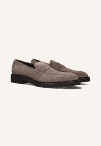 Een paar taupe suede penny loafers met donkere rubberen zolen, schuin naar links op een effen lichte achtergrond.