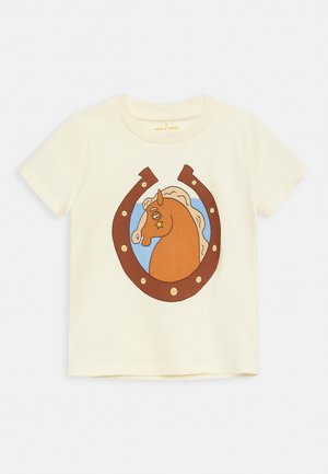 T-shirt enfant couleur crème avec une tête de cheval marron à l'intérieur d'un fer à cheval marron sur fond bleu.