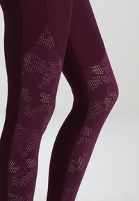 Leggings borgogna con dettagli in rete a motivo puntinato, tessuto testurizzato, design aderente e cuciture sagomate per un look su misura.