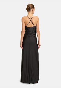 Czarna, bezrękawna długa sukienka z dopasowanym gorsetem, krzyżującymi się ramiączkami i zamkiem błyskawicznym z tyłu. Gładki materiał o lekko połyskującej powierzchni i długości do podłogi.