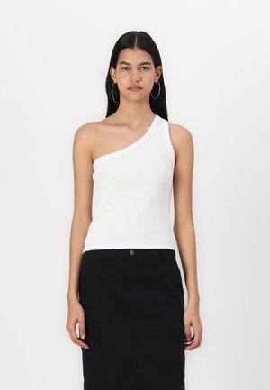Top in cotone bianco a coste asimmetrico con una sola spallina, abbinato a una gonna nera a ginocchio con tasche laterali.
