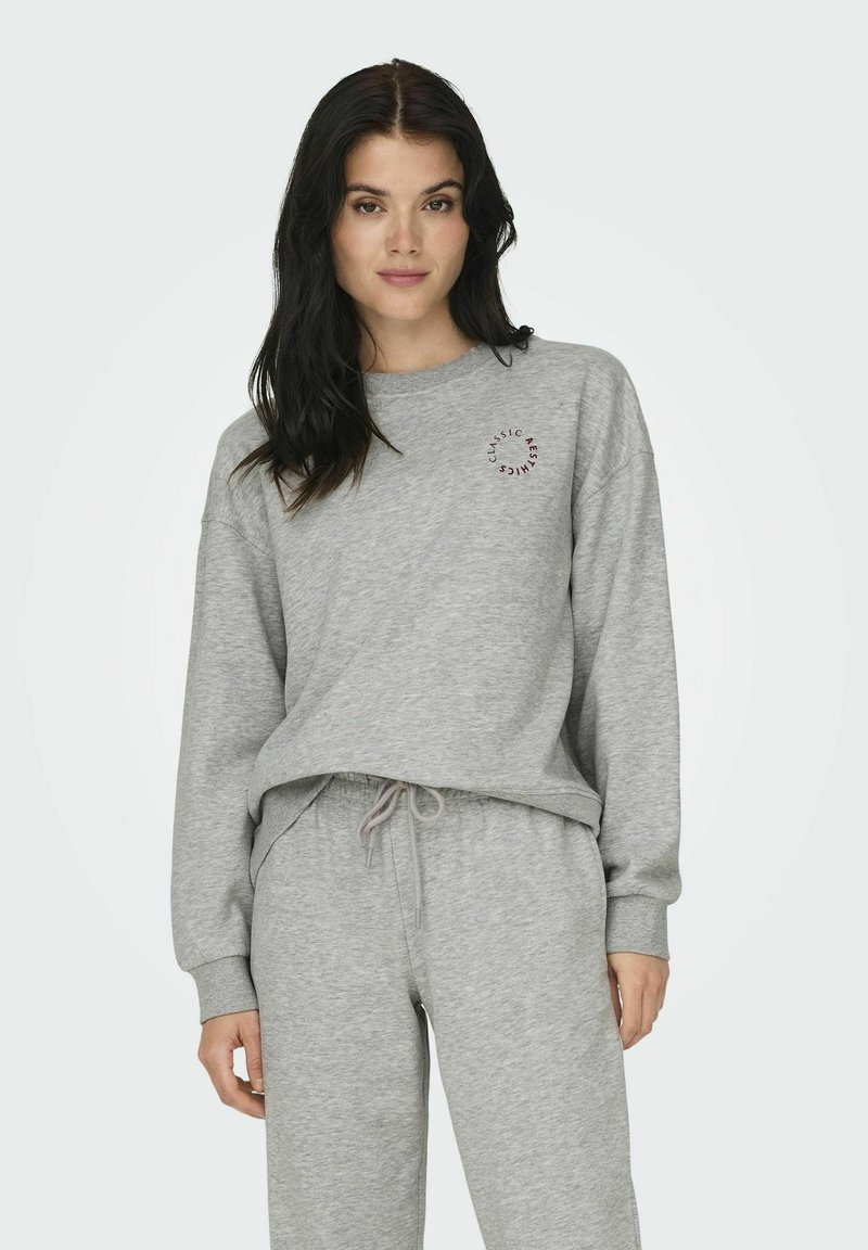 Grijze sweatshirt met lange mouwen en een ronde halslijn, voorzien van een klein, rond logo op de borst. Gecombineerd met bijpassende grijze joggingbroek.