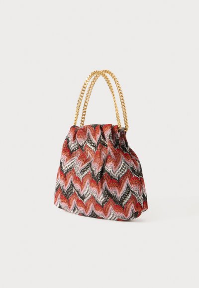 Sac en tissu avec un motif en zigzag dans des tons rouges, noirs et blancs ; dispose d'un haut froncé et de poignées en chaîne dorée.