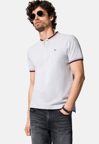 Szary polo z czerwonym i granatowym ściągaczem, z trzema guzikami i haftowanym logo na piersi. Miękki materiał, krótkie rękawy.