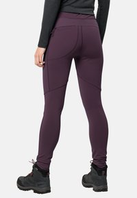 Lila träningsleggings med hög midja, med accentuerande sömmar och en liten ficka, i kombination med mörka vandringskängor.