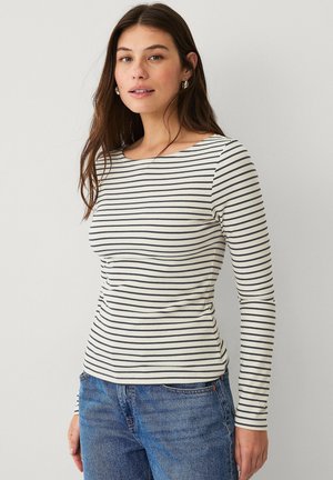 Haut léger à manches longues en crème avec des rayures horizontales bleu marine, doté d'un col rond et d'une texture côtelée, associé à un jean en denim.