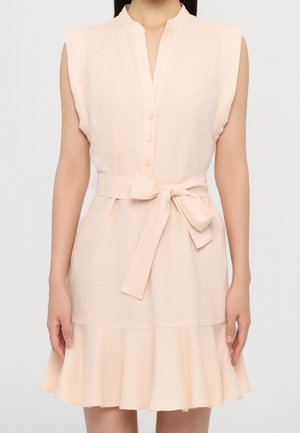 Robe sans manches d'un pêche clair avec un col rond, des boutons sur le devant, une ceinture nouée et un ourlet froncé. Fabriquée en tissu doux et texturé.