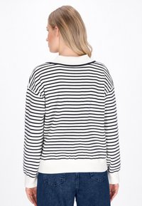 Maglione a righe in bianco e blu marino, con scollatura rotonda e polsini a costine. Presenta una vestibilità rilassata e una morbida trama a maglia.