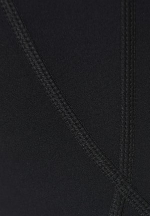 Close-up van zwarte stof met twee elkaar kruisende naden, gestikt met bijpassend zwarte draad.