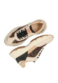Zapatillas beige y marrón con acentos negros, materiales de ante y cuero, diseño con cordones, suelas texturizadas y detalle del logo en el lateral.
