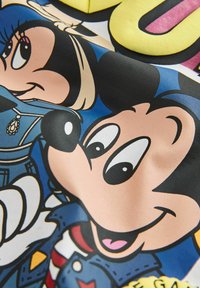 Les personnages de dessins animés Mickey et Minnie Mouse portant des tenues bleues avec un texte coloré en arrière-plan sur une surface en tissu.