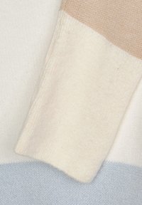 Stickad tröja med tre horisontella ränder: krämfärgad, beige och ljusblå. Mjuk textur, slät yta, lätt material.