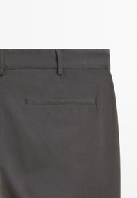 Mørkegrå bukser med en glat tekstur, der har en flad talje og en baglomme. Minimalistisk design uden synligt hardware eller accenter.