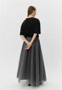 Must musta, millega on ühendatud pikk, voolav hall tüllseelik. Rõivastusel on loomulik vöökoht ja peen elastne vöö.