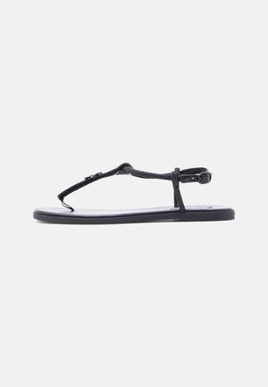 Sort thong-sandal med en flad sål, der har en vævet rem og justerbar ankelspænde for en sikker pasform. Glat gummimateriale.