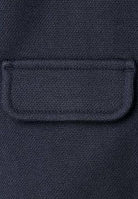 Material texturat de culoare bleumarin închis, cu un buzunar dreptunghiular aplicat pe suprafață, având cusături întărite de-a lungul marginilor.