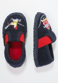 Marinefarbene Filzhausschuhe mit roten elastischen Bändern; versehen mit gestickten Designs eines Charakters und eines Fahrzeugs, strukturierte Sohle für Grip.