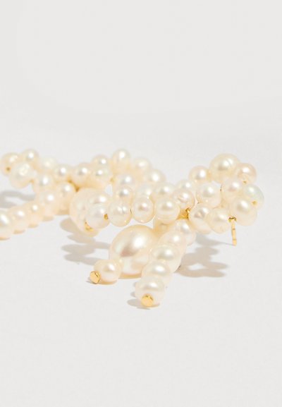 Brincos de pérola branca apresentam uma variedade de tamanhos e formas, com acentos dourados e acabamento suave e lustroso.