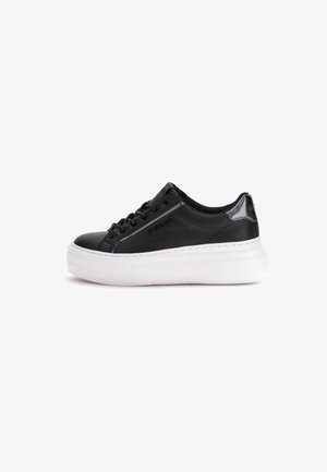Zapatilla baja de cuero negro con suela de plataforma blanca, cordones negros y logo de la marca en el lateral y el talón.