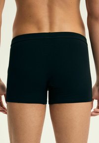 Czarne bokserki z elastycznego materia�łu z prostym wzorem i elastycznym pasem, charakteryzujące się dopasowanym krojem i gładką teksturą.