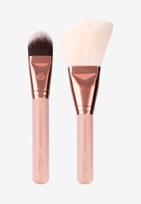 Dos brochas de maquillaje: una tiene un cabezal de cerdas negras densas y suaves; la otra presenta una cerda ancha y plana de color blanco. Ambas tienen detalles en oro rosa y mangos rosas.