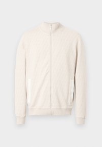 Lys beige jakke med glidelås og høy hals, med et teksturert diamantmønster, ribbestrikkede mansjetter og to sidelommer med hvite detaljer.