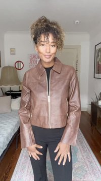 Brown leather jacket with a zip front, structured collar, and long sleeves. Features side pockets and smooth texture.
