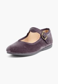 Zapato plano de terciopelo púrpura con punta redondeada, una cinta elástica con una hebilla dorada y una plantilla texturizada. Suela de goma para mayor agarre.