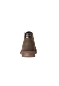 Botas de cuero marrón hasta el tobillo con un acabado liso, punta redonda y un tacón bajo apilado. Presenta una etiqueta de cuero con la marca en la parte trasera.