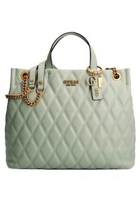 Sac à main matelassé vert menthe avec des bandoulières à chaîne en or, logo GUESS, et des étiquettes décoratives portant les inscriptions "G" et "1981" sur le devant.