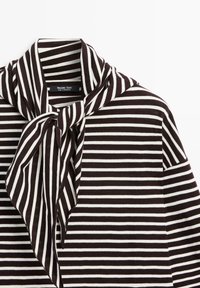 Sort-hvid, vandret stribet sweater med en stor bundet sløjfe ved halsen, med et Massimo Dutti-mærke indeni kraven.