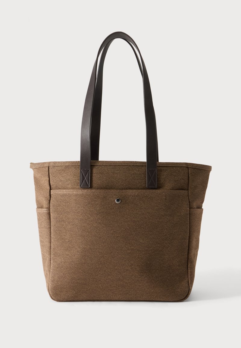 Sac cabas en tissu marron avec des lanières d'épaule en cuir marron foncé et une poche avant avec une fermeture à bouton-pression unique.