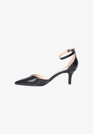 Scarpa nera in pelle con punta affusolata, tacco basso, cinturino alla caviglia e fibbia, mostrata di profilo su sfondo bianco.