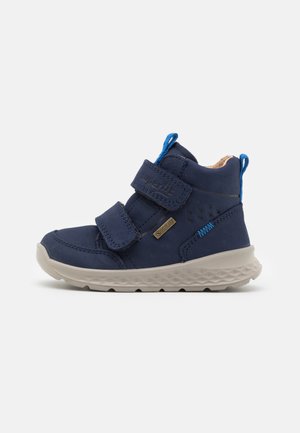 Botte pour enfants bleu marine avec deux sangles Velcro, tige texturée et une semelle gris clair présentant un motif en losanges et des coutures bleu contrastant.