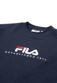 Granatowa bluza z prążkowanym, okrągłym dekoltem, ozdobiona czerwono-białym haftowanym logo z napisem "FILA ESTABLISHED 1911".