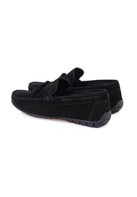 Schwarze Wildleder Slipper mit einer flexiblen Gummisohle, die mit einer dekorativen Schleifenakzent und gestickten Details entlang der Kanten versehen sind.