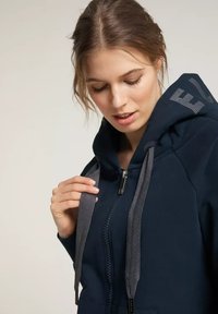 Dunkelblaues Zip-Hoodie aus weichem Stoff, mit einer Kapuze mit Kordelzug in Grau und einem Logo auf dem Rücken. Glatte Textur.