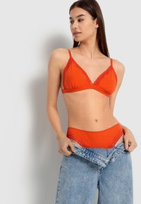 Brassière en dentelle rouge avec bordure de dentelle et culotte assortie, offrant un tissu doux et une texture légère, avec un design taille haute et une coupe ajustée.