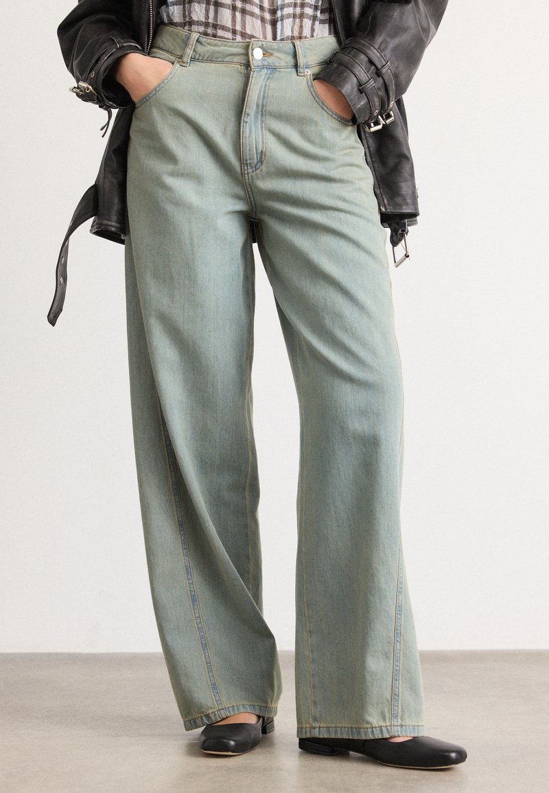 Lyseblå vide denimjeans med høyt liv, frontlommer, knappefeste og en lett falmet finish.