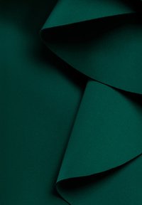 Tummanvihreä kangas, jossa on sileä tekstuuri ja päällekkäisiä laskoksia, jotka luovat kerroksellisen vaikutelman. Ei näkyviä kuvioita tai kiinnikkeitä.