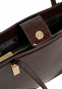 Brown patent leather handbag with crocodile embossing, gold hardware, magnetic flap closure, and zippered interior pocket.