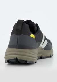 Scarpa sportiva nera con tomaia in rete, dettagli in gomma e suola grigia. Presenta un dettaglio giallo e un linguetta sul tallone per indossarla facilmente.