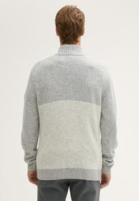 Grijs gespikkeld sweater met een hoge kraag en geribbelde manchetten. Kenmerkend is het twee-tonen ontwerp, dat donkergrijze en lichter grijze tinten combineert.