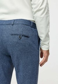 Donkerblauwe gestructureerde broek van geweven stof, met een achterzak met knoopsluiting en een rechte pasvorm.