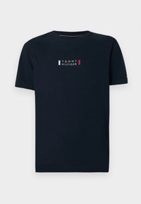 Μπλε βαμβακερό T-shirt με κοντά μανίκια, που διαθέτει ένα λογότυπο με κόκκινες και λευκές ρίγες και έντονο κείμενο στο κέντρο.