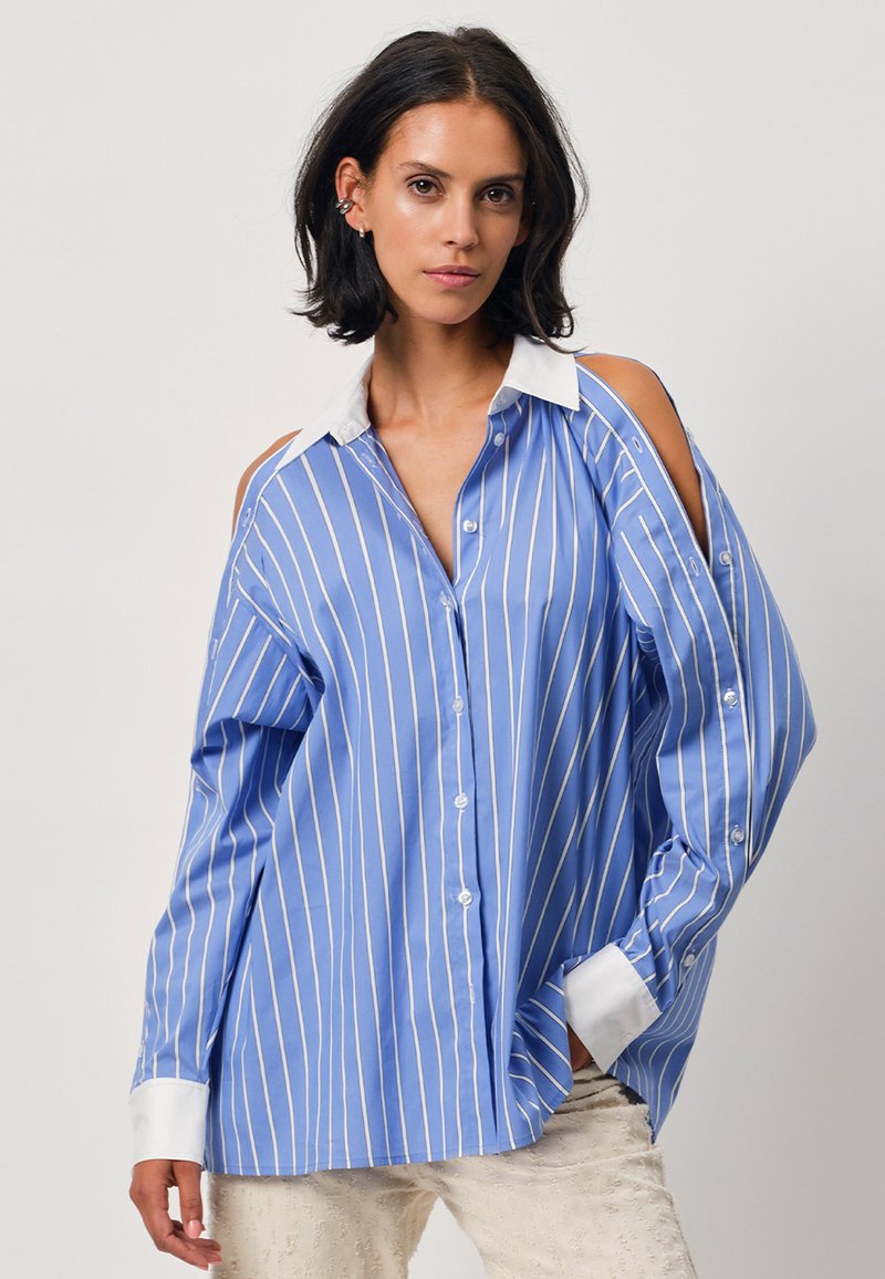 Blue and white striped button-up shirt with cold shoulder design, collar, and long sleeves. Made of lightweight fabric, relaxed fit.