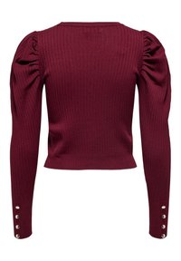 Burgunderfärgad ribbad tröja med lång ärm och knappdetaljer vid manschetterna, samt en figurnära och kort design. Strukturerad tyg genomgående.