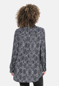 Zwarte en grijze slangenprint met lange mouwen, voorzien van een kraag, een relaxte pasvorm en een gebogen zoom, geschikt voor het laagjeslook.